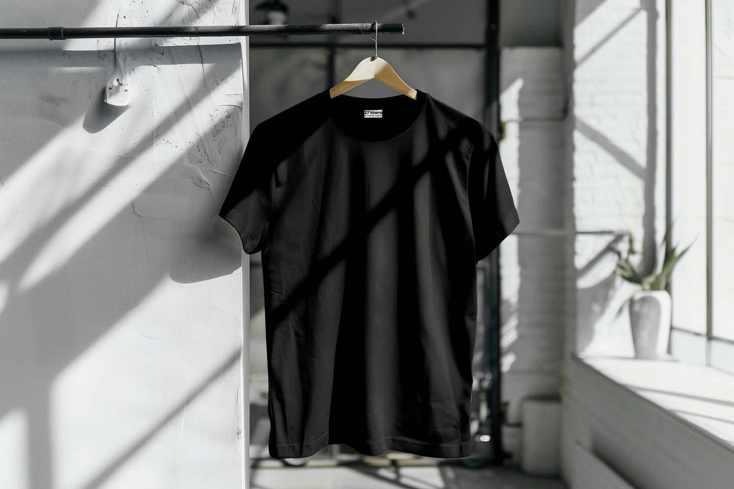 Plain black T-shirt hanging on a wooden hanger in a sunlit modern interior. Stylish and versatile, perfect for casual wear.