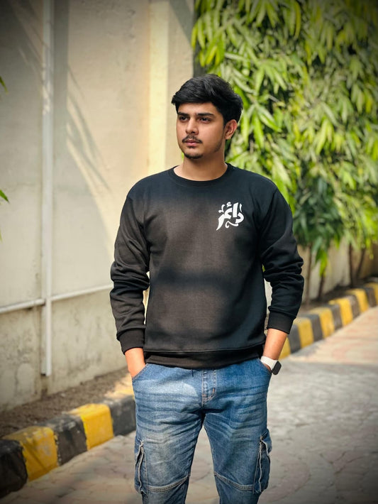 Black calligraphy sweatshirt with white Arabic design, worn by a male model outdoors. Premium fabric for comfort and style, available in Pakistan.